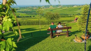 A couple sitting on a bench overlooking a green landscape with rolling hills and a clear sky. - Villa 'Casa Vacanze Elios B' with Mountain View, Wi-Fi and Air Conditioning (Unknown)