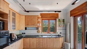 A modern kitchen with wooden cabinets, a built-in oven, and a large window with a view.