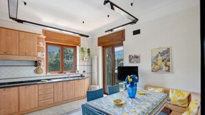 A modern kitchen with wooden cabinets, a dining area with a table and chairs, and a large window with a view.