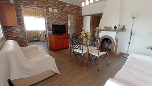 A cozy living room with a fireplace, a dining table with chairs, a sofa, and a television. - Villa Pablo - Chalet en Vinaròs - Ref. 017 (Vinaròs)