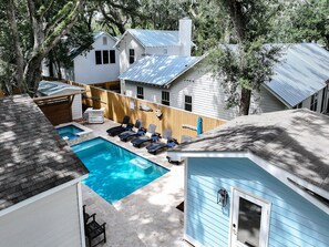 A backyard with a swimming pool, lounge chairs, and a wooden deck. - Porch Light Cottage - Historic District Walk to the Beach, Private Pool, Spa, Fire Pit & Guest House (Saint Simons Island)