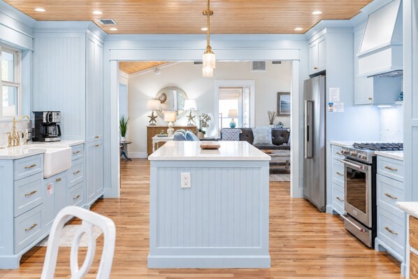 A spacious kitchen with a central island, wooden flooring, and light blue cabinetry.
