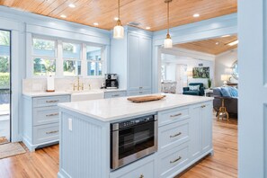 A spacious kitchen with light blue cabinetry, a central island with a built-in oven, and a coffee machine.