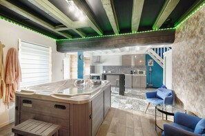 Un intérieur moderne comprenant un jacuzzi, une cuisine et un coin salon avec des canapés bleus.