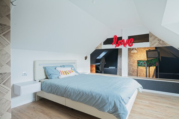 Un dormitorio con cama, mesita de noche, espejo y un letrero en la pared que dice 'Love'.