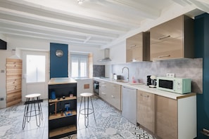 Una cocina moderna con una isla central, taburetes de bar, un microondas y un fregadero.