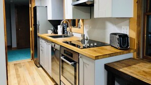 Eine kleine Küche mit Spüle, Herd und Toaster. Es gibt eine Holz Arbeitsplatte und weiße Schränke.