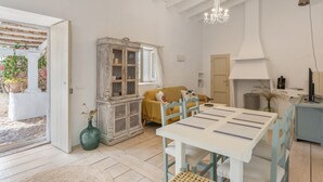 Una habitación con una mesa de comedor, sillas, un armario, un sofá y una araña.