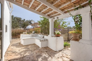 A covered outdoor seating area with stone flooring, white walls, and a pergola. - Country Cottage 'Vicent' with Private Terrace and Garden (Illes Balears)