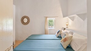 Una habitación con dos camas, una ventana con cortinas, un espejo colgado en la pared y una mesita de noche con lámpara.
