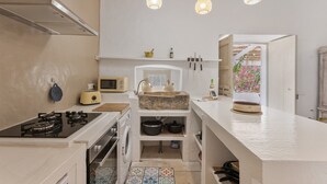 Cocina compacta con estufa a gas, microondas y horno empotrado. Incluye un lavabo con pileta de piedra y una pequeña ventana con vistas a flores.