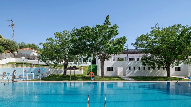 Una piscina con una postazione per bagnini, un trampolino e una recinzione.