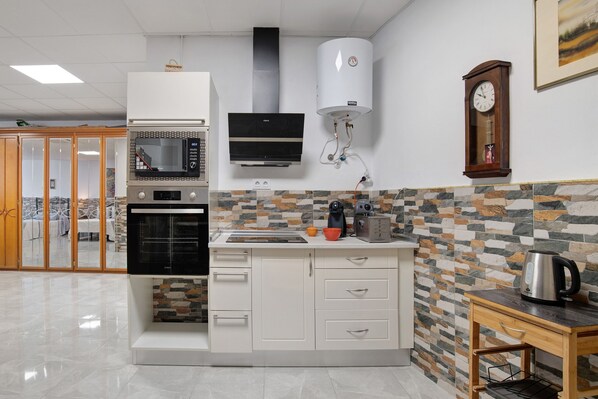 A modern kitchen with built-in appliances, a stone-patterned backsplash, and a wooden table with a kettle.