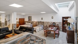 Un'ampia zona giorno con soffitto alto, un lucernario, un tavolo da pranzo e un camino.