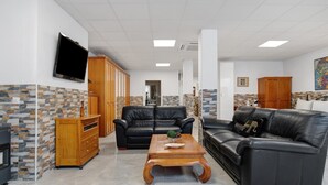 Un soggiorno moderno con un divano in pelle nera, un tavolino in legno e una TV a parete.