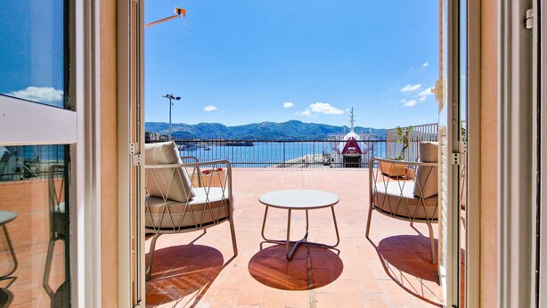 An outdoor patio with two chairs and a table, a view of the sea, and a mountain range in the background. - Apartment 'Terrazza Sul Mare' with Sea View, Wi-Fi and Air Conditioning (Portoferraio)