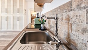 A kitchen with a stainless steel sink, wooden cabinets, and a backsplash with city names. - Apartment 'Terrazza Sul Mare' with Sea View, Wi-Fi and Air Conditioning (Portoferraio)