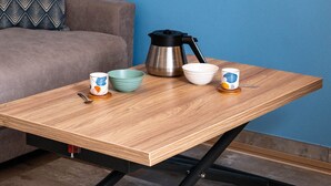 Una mesa de madera con una cafetera, tazones y tazas.