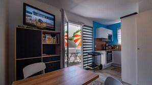 Un espacio habitable compacto con comedor, kitchenette y televisor en la pared.