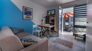 Una sala de estar con un sofá, una mesa de centro, un televisor y una estantería.