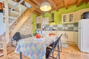 A kitchen with wooden beams, a staircase, and a dining table with a patterned tablecloth.