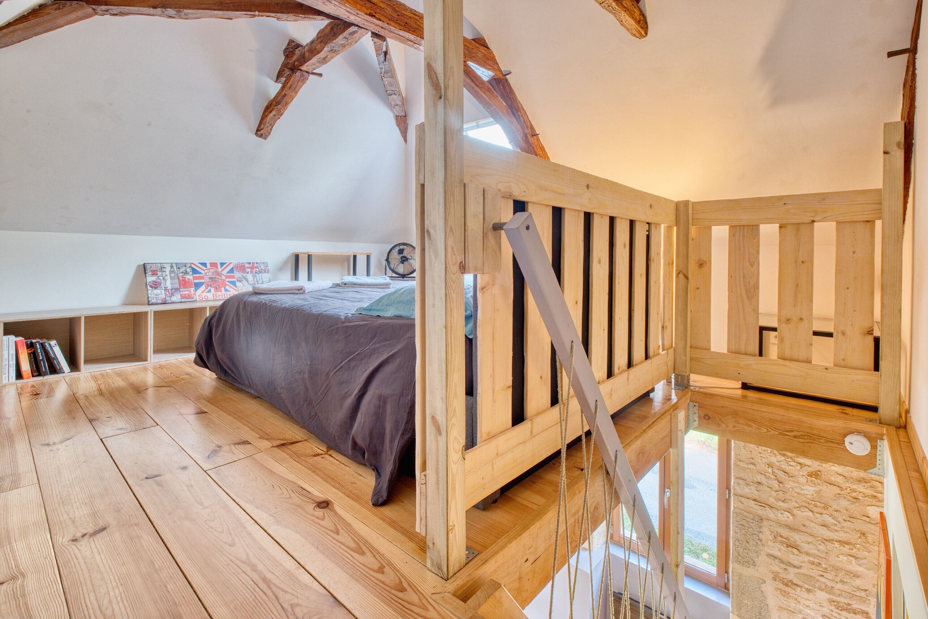 Une chambre avec un plafond en bois, un lit, une fenêtre et un plancher en bois.