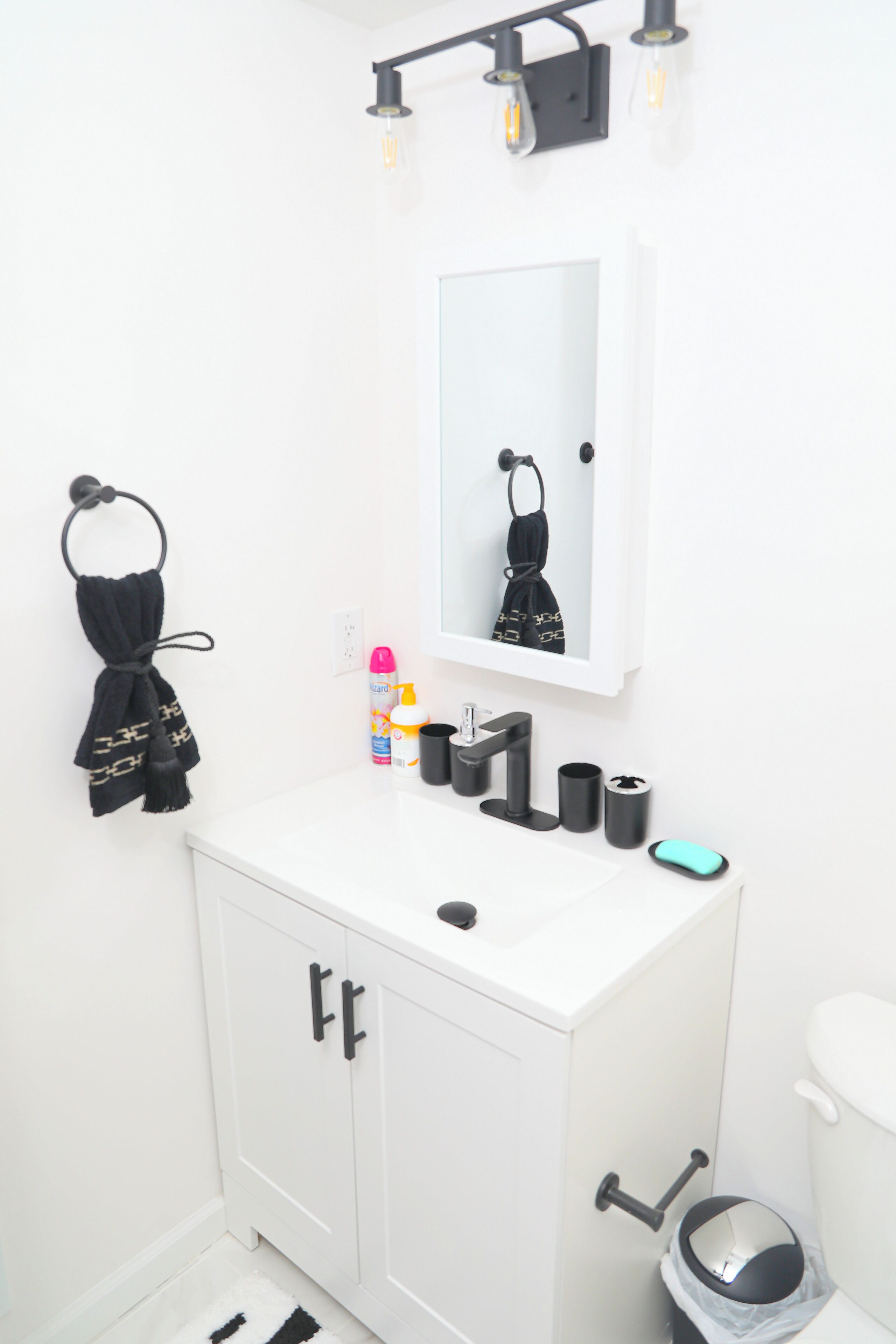 A bathroom with a white sink, black towel, and a mirror above it.