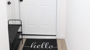 A white door with a '1' above it, a welcome sign, and a black doormat with "hello" on it. - Upscale 3-bedroom/2.5-bath unit near EWR, NYC, MetLife, Prudential, and more. (Newark)