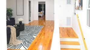 A modern living room with a black sofa, a zebra-patterned rug, and a potted plant. - Upscale 3-bedroom/2.5-bath unit near EWR, NYC, MetLife, Prudential, and more. (Newark)