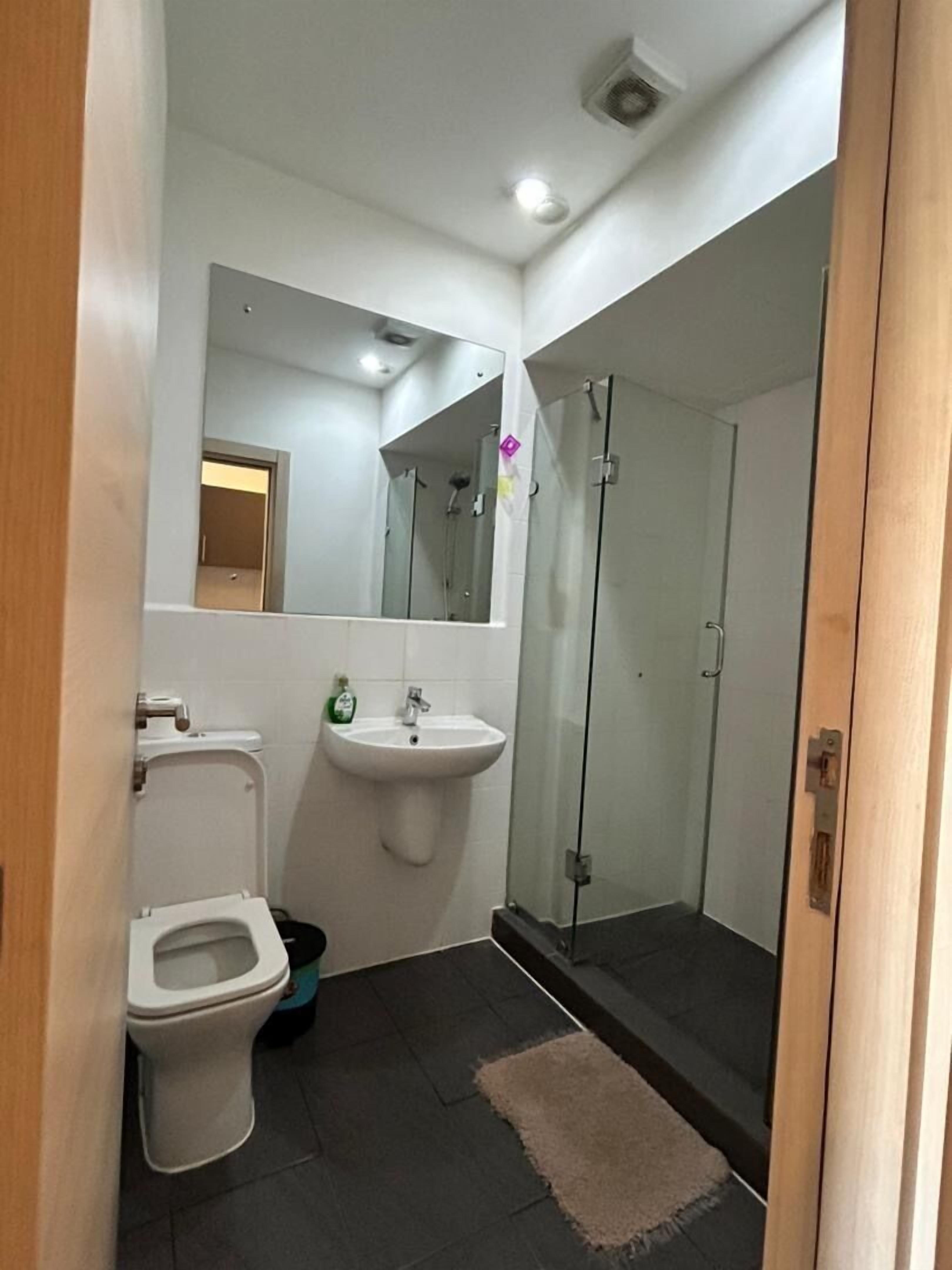 A modern bathroom with a toilet, sink, and glass-enclosed shower.