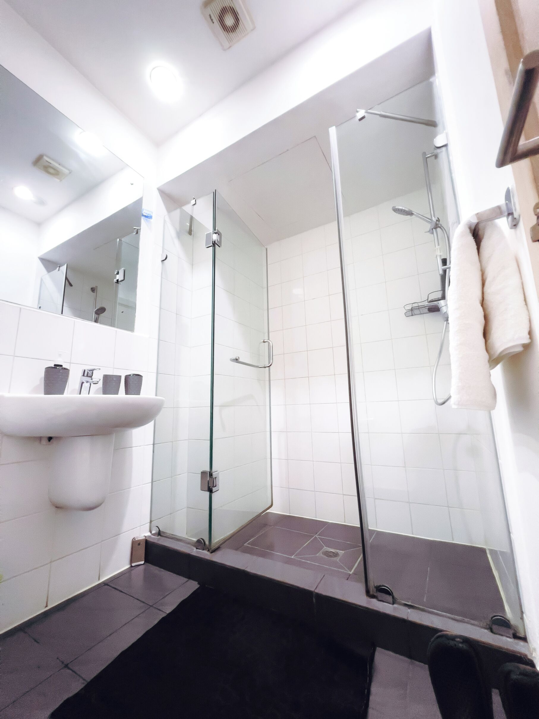 Une salle de bain moderne avec une douche à parois de verre, un lavabo blanc et un miroir.