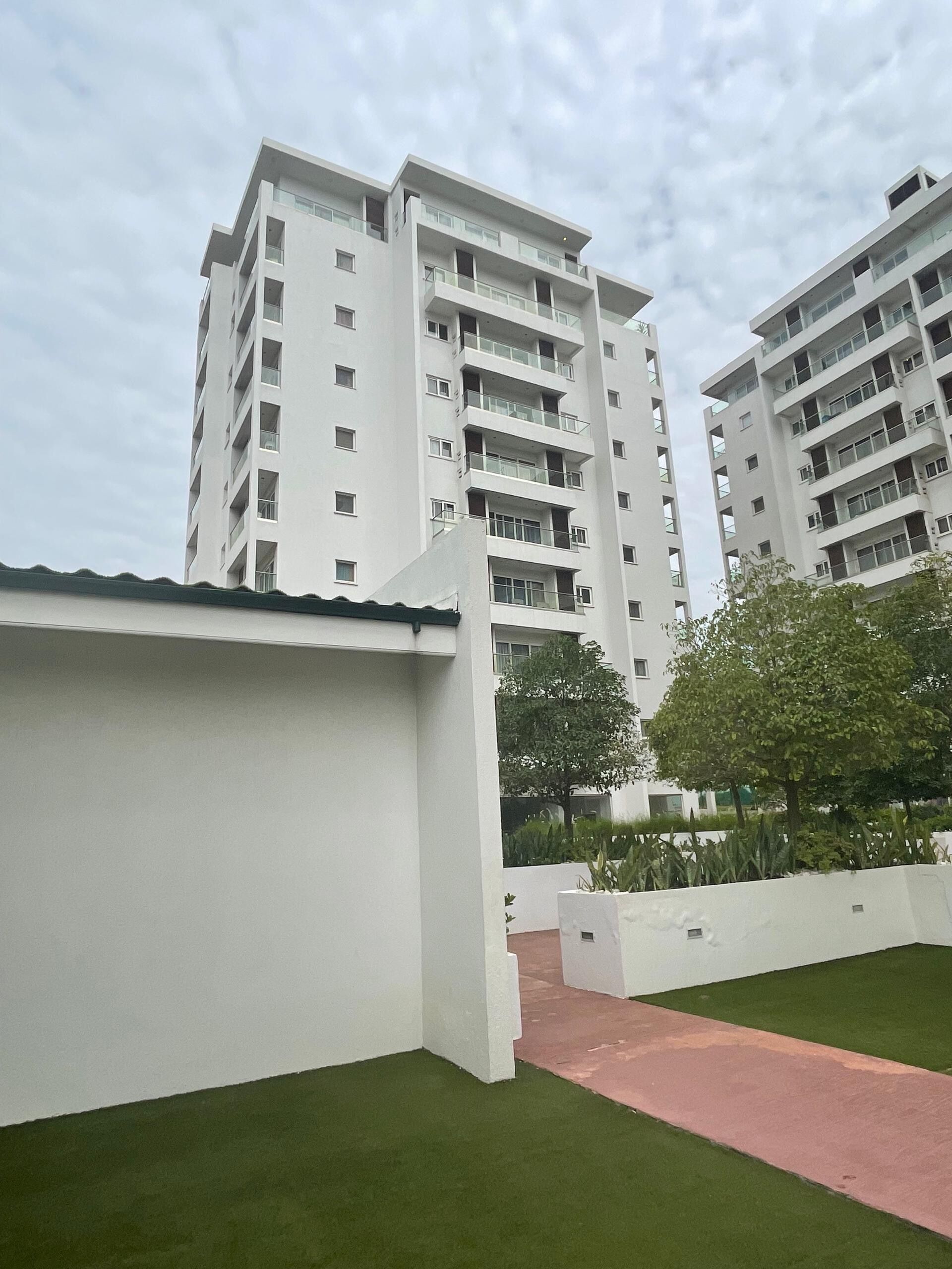 A modern residential building with multiple balconies and a flat roof.
