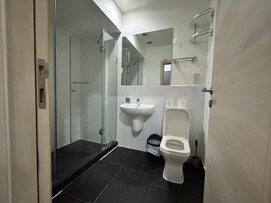 Une salle de bain moderne avec une douche à parois de verre, un lavabo blanc et des toilettes.