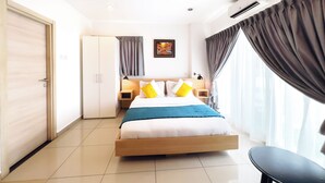 Habitación de hotel con cama, escritorio, silla, armario y ventana con cortinas.