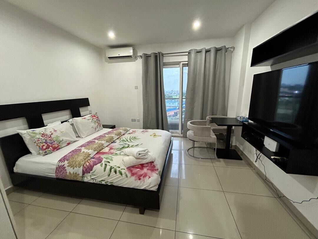 A hotel room with a bed, a TV, a desk, and a chair.