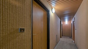Un pasillo con paredes y puertas de madera, suelo alfombrado y techo de listones.