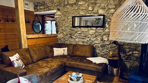 Un salon chaleureux avec un mur en pierre, un plafond en bois et une grande lampe en fibres tressées.