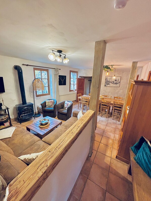 Un salon chaleureux avec un canapé, une table basse et une cheminée. Il y a également un coin repas avec une table et des chaises.