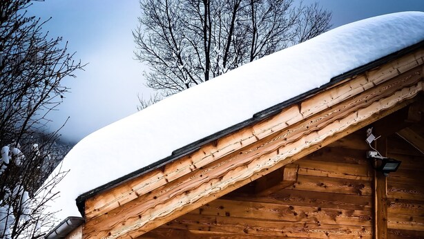 Une cabane en bois avec un mur en pierre, une porte en bois et une fenêtre.