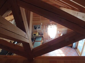 A wooden interior with a sloped ceiling, a kitchen area with a stove and sink, and a dining table with chairs.