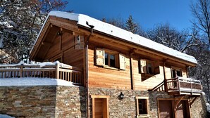Une maison en bois à deux étages, avec des fondations en pierre, des balcons en bois et un mur en pierre.