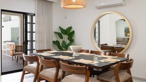A dining area with a round table, wooden chairs, a large mirror, and a hanging light fixture. - Casa Kathy: Exquisite 6BR, 11 Bed & 26 Guests (Mazatlán)
