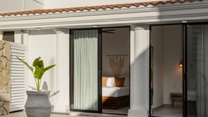 A modern hotel room with a bed, a large window, and a sliding glass door leading to a balcony. - Casa Kathy: Exquisite 6BR, 11 Bed & 26 Guests (Mazatlán)