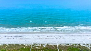 A beach with clear blue water and a sandy shore.