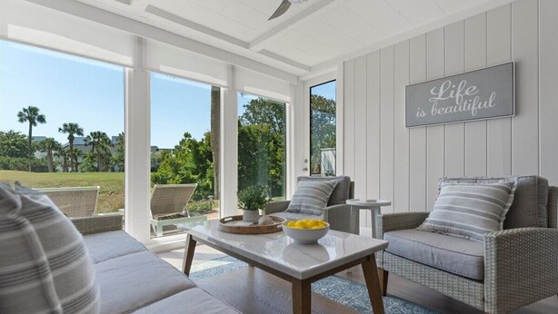 A modern living room with a large window, a sofa, a coffee table, and a wall-mounted sign.