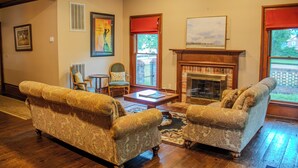 A living room with two patterned sofas, a fireplace, and a view of the outside. - The Rose Room - Charming Private Studio w/ Ensuite Bath in Historic Home (Clinton)