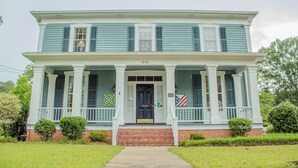 A two-story house with a front porch, a brick foundation, and a number '615' above the door. - The Rose Room - Charming Private Studio w/ Ensuite Bath in Historic Home (Clinton)