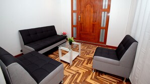 A living room with a black sofa, a grey sofa, and a white coffee table.