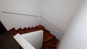 A staircase with wooden steps and metal handrails, leading to an upper floor.