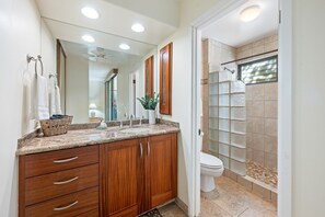 A bathroom with a wooden vanity, a glass shower enclosure, and a white toilet.